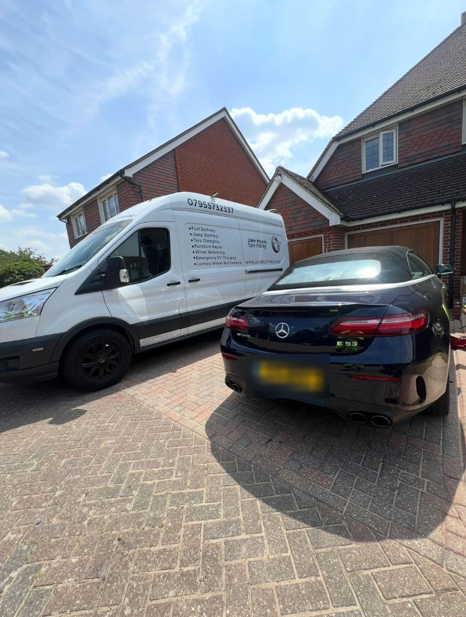 A dark blue Mercedes convertible on a block-paved drive beside a JL Mobile Tyres van