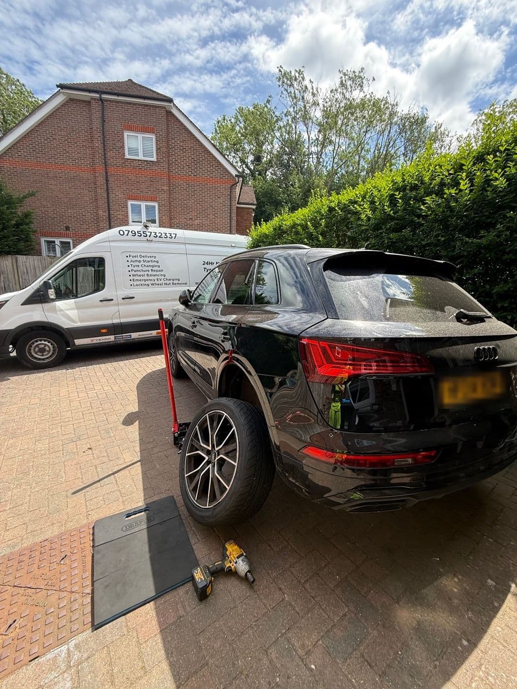 A black Audi Q5 on a block-paved drive with one wheel off, a JL Mobile Tyres van parked behind