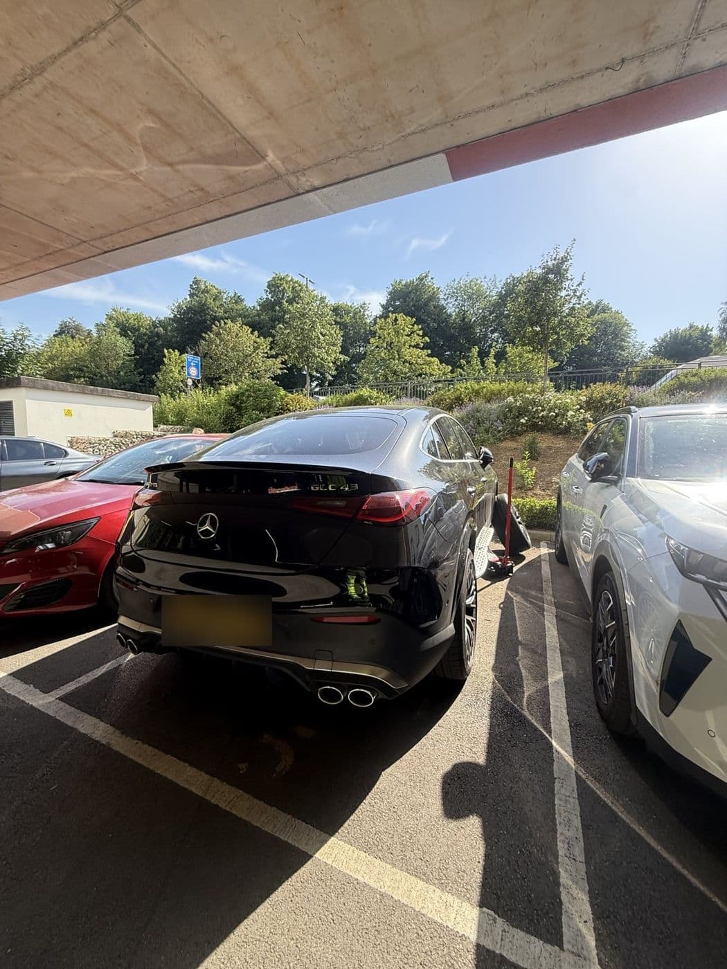 A black Mercedes-AMG coupé SUV in an open car park with a jack by its rear wheel
