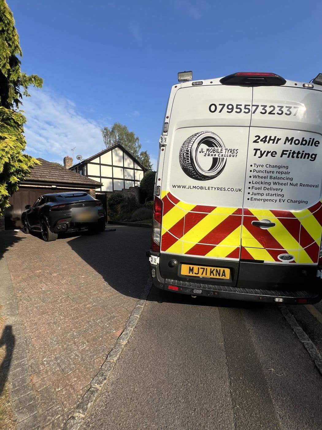 Rear of a JL Mobile Tyres van with red and yellow chevrons and the phone number on the back doors