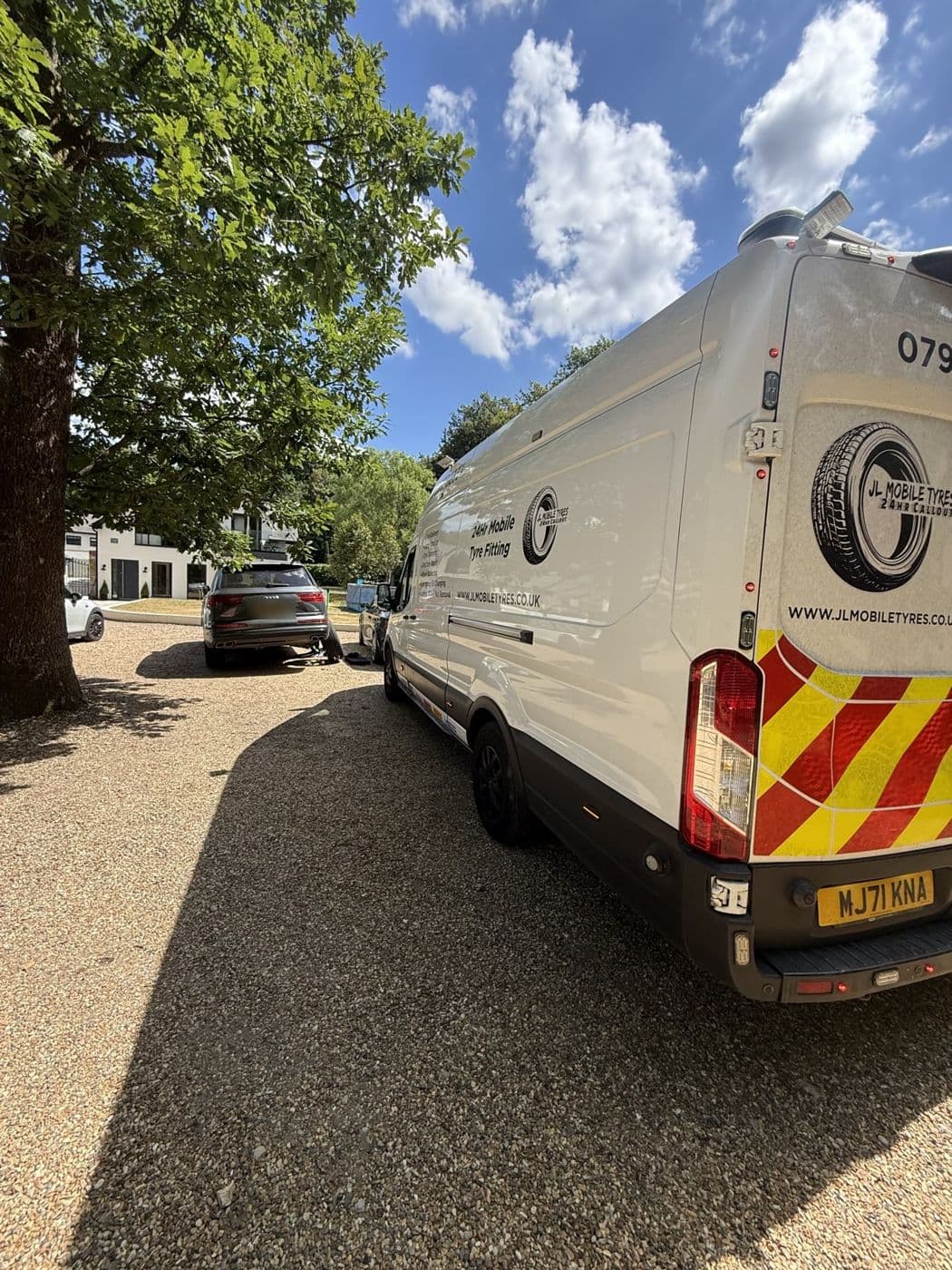 A JL Mobile Tyres van on a gravel drive behind a grey Audi Q7 that has a wheel off