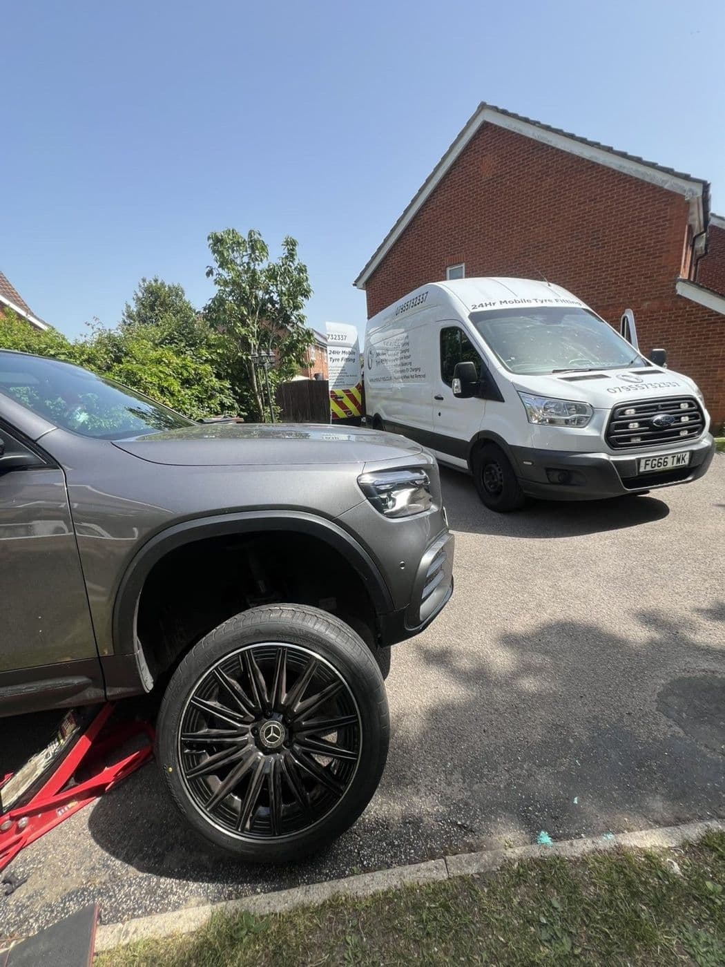 Mercedes X-Class jacked up on a driveway for a tyre change, with a JL Mobile Tyres van parked behind